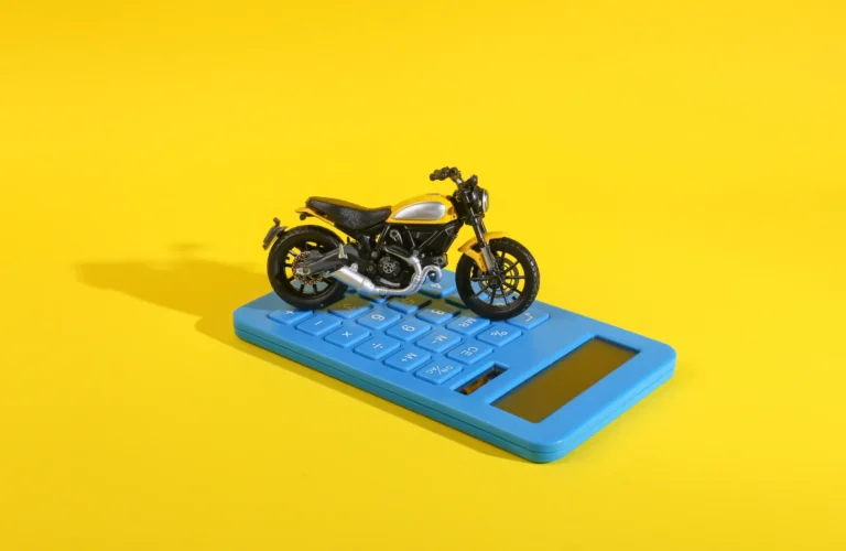 Toy motor bikes on calculator with yellow background, symbolizing bike price, EMI, and fuel cost calculator – GenieBikez